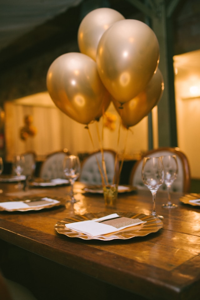 Mesa de celebración con globos dorados y vajilla elegante para evento especial